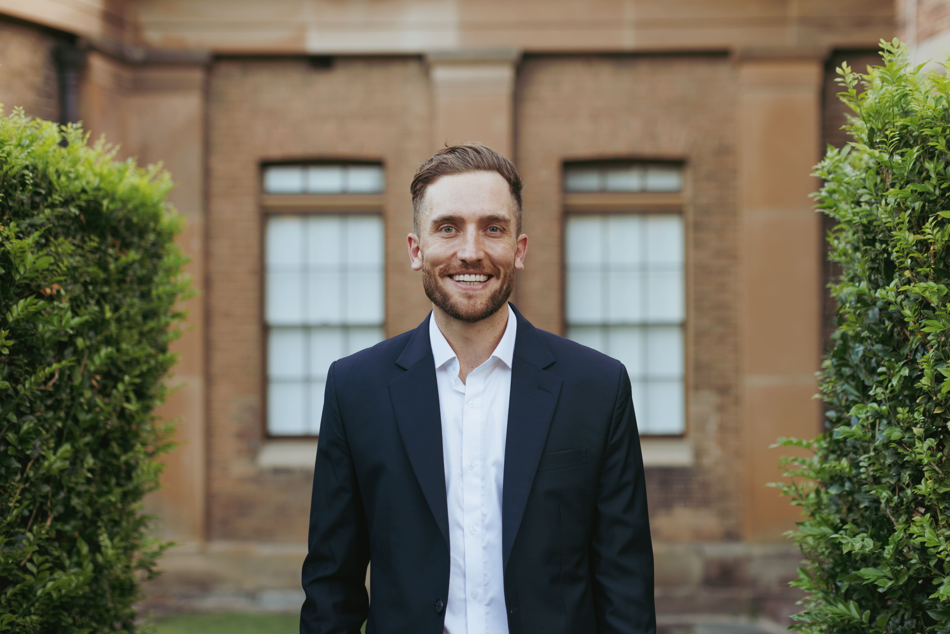 Professional headshot of Andy Crebar in a suit with a brick background